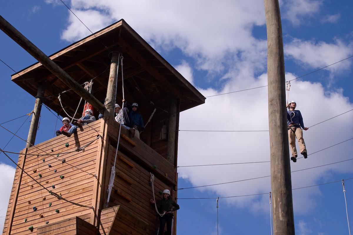 Students sit in a high ropes course tower, atop a rock wall at 金沙全球赢家信心之选4066